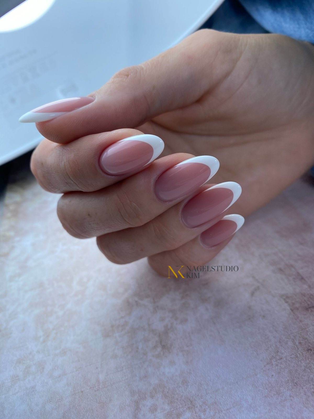 French nagels met een witte rand op een roze marmeren ondergrond